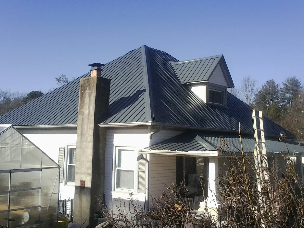 Dark blue standing seam metal roof on a white farmhouse with dormer — Slate & Tile Roof Repair by Roofing Brothers in Childersburg