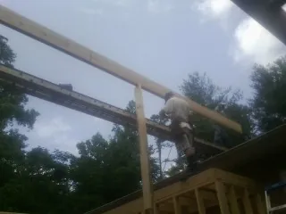 Carpenter setting a ridge beam over a new addition frame — Ice Dam Removal by Roofing Brothers in Childersburg