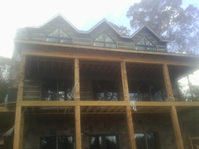 Dormers and porch framing on a large log home under construction — Roof Coating work by our crew in Childersburg