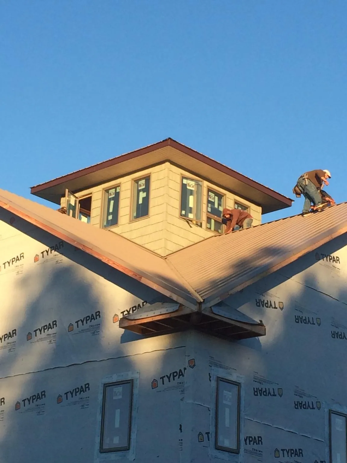 Roofers working around a rooftop cupola on a new metal roof at sunset — Roof Waterproofing in Childersburg by Roofing Brothers